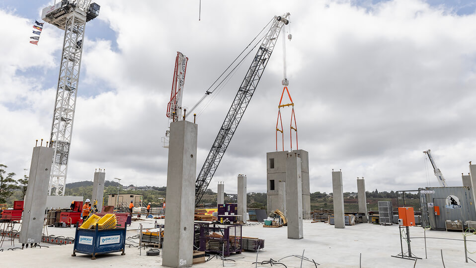 Construction workers and cranes assembling concrete columns on the New Toowoomba Hospital building site.