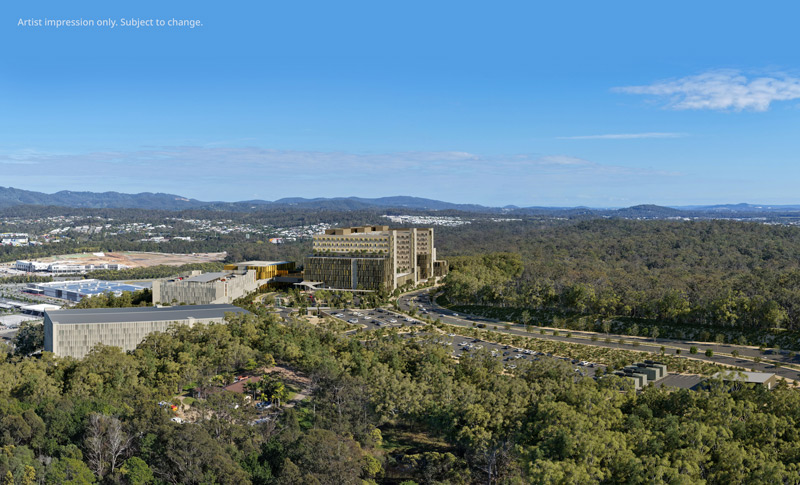 Wide aerial view of the Coomera Hospital site with concrete structures rising and surrounding landscape and suburbs visible.