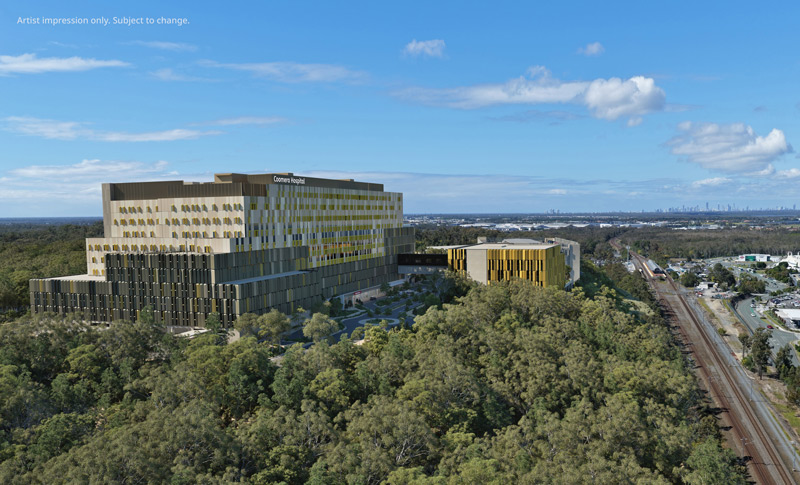 Aerial image of the Coomera Hospital build showing multiple concrete cores and site activity against a backdrop of bushland and businesses.