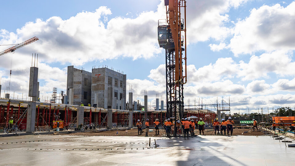 Construction workers gather around a tower crane as concrete is prepared and poured on the QEII Hospital expansion site.